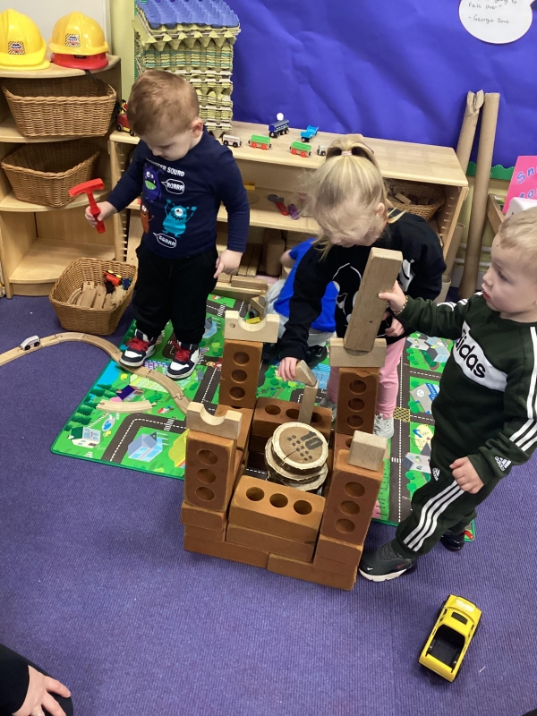 Three children build a castle out of building blocks